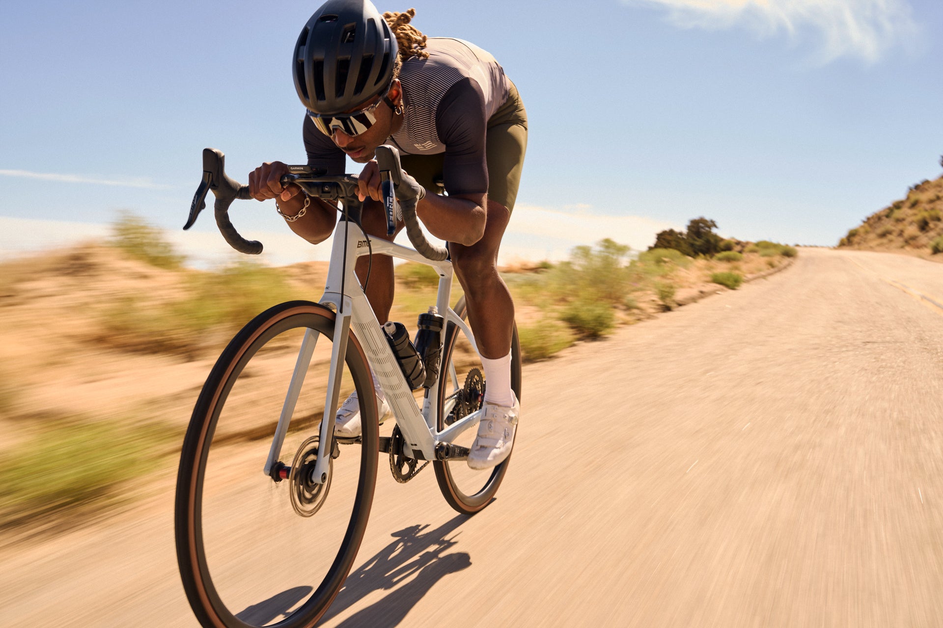 Cyclist riding on a desert road with a clear sky